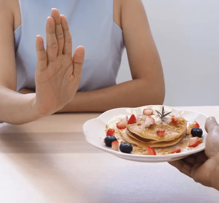 A person declining a plate of pancakes, illustrating appetite awareness